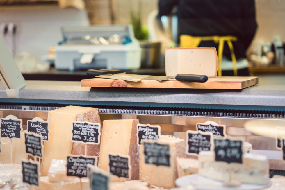 Refrigerated deli case filled with cheeses and price cards